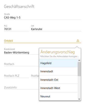 Der Screenshot zeigt den Block Geschäftsanschrift. Ein gelbes Warnsymbol bei einem Feld weist auf einen Änderungsvorschlag hin, darunter sehen Sie die Korrekturvorschläge.